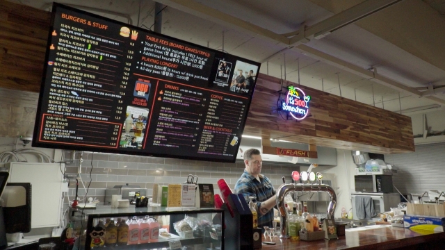 Joey Croner, owner of Dice and Comics Cafe, pours a beer behind the counter. (The Korea Herald)