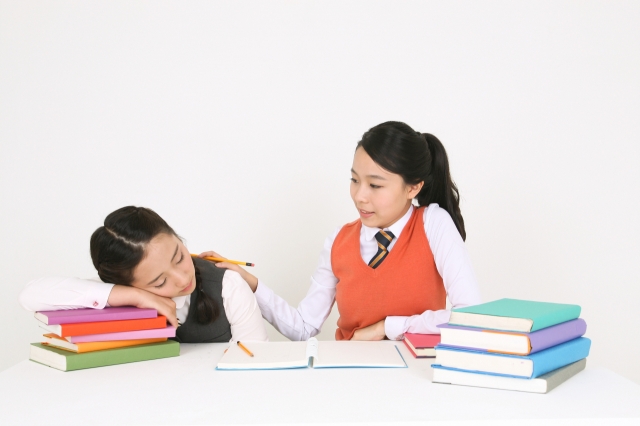 A student tries to wake up her friend who has dozed off. (123rf)