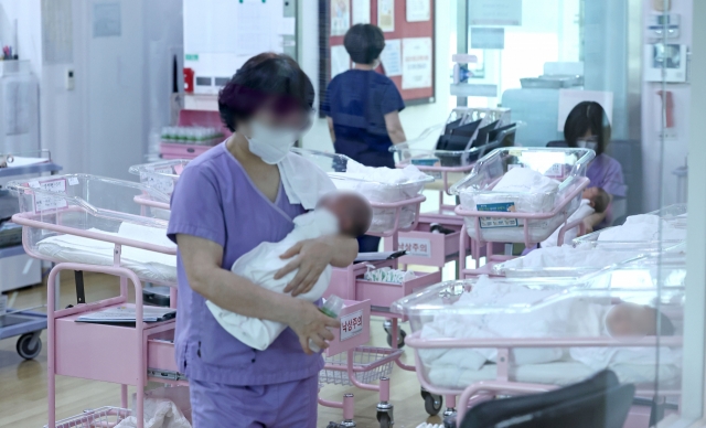 An employee at a postpartum care center in Seoul holds a newborn baby in this file photo. (Yonhap)