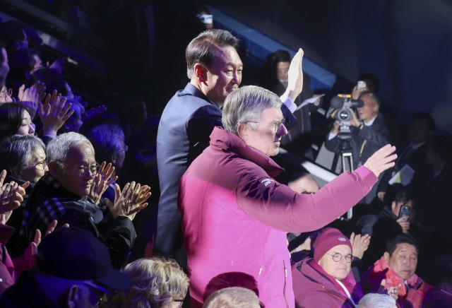 President Yoon Suk Yeol (left) and Thomas Bach, president of the International Olympic Committee, wave to the audience during the opening ceremony for the Winter Youth Olympics held in Gangneung, some 160 kilometers east of Seoul, on Friday. (Yonhap)