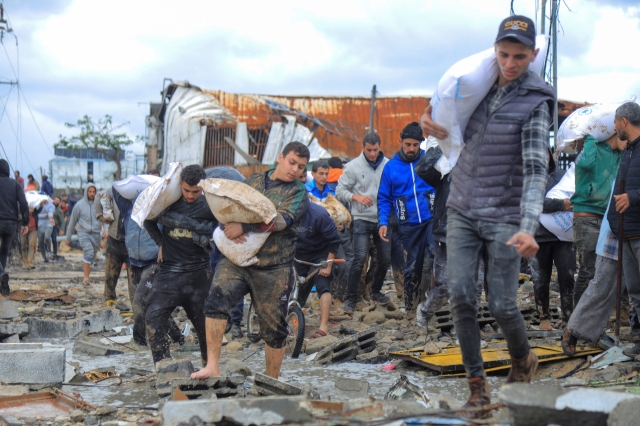 Palestinians carry bags of flour they grabbed from an aid truck near an Israeli checkpoint, as Gaza residents face crisis levels of hunger, amid the ongoing conflict between Israel and Hamas, in Gaza City on Saturday. (Reuters-Yonhap)