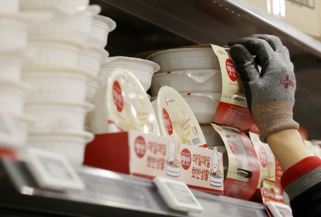 A supermarket clerk stocks instant rice on a shelf. (Newsis)