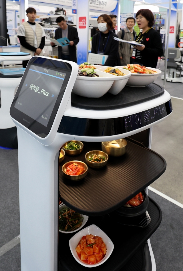 Visitors take a look at a service robot during a convention held in Daegu on Nov. 14. (Newsis)