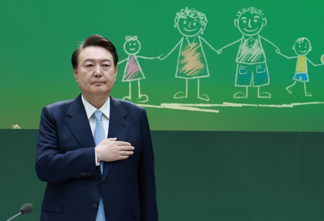 President Yoon Suk Yeol salutes the national flag as he presides over a public debate at an elementary school in Hanam, Gyeonggi Province on Monday. (Yonhap)