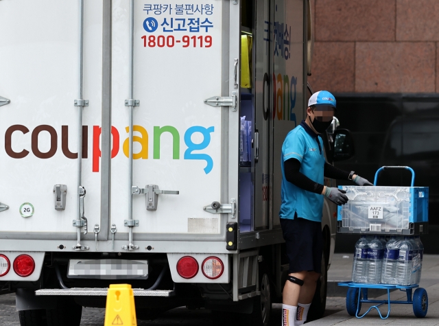 A Coupang delivery worker unloads delivered goods from a truck. (The Korea Herald)