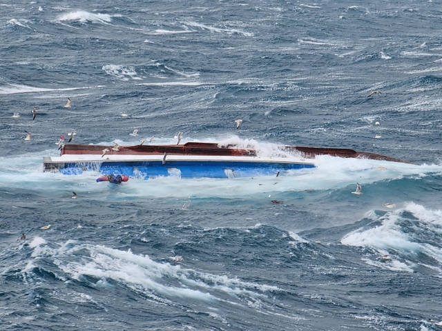 This image provided by the Coast Guard shows a fishing boat that capsized in waters off the southern island of Jeju on Friday. (Yonhap)