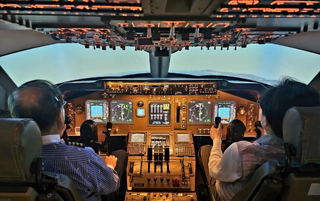 A participant copilots a plane next to a veteran pilot during a flight simulator program at the National Aviation Museum of Korea. (Choi Si-young/The Korea Herald)