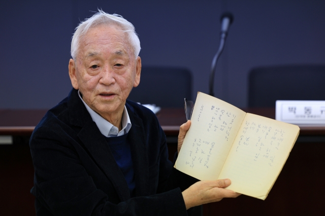 Park Dong-gyu holds up one of the notebooks of his father, the late poet Park Mok-wol, during a press conference in Seoul on Tuesday. (Yonhap)