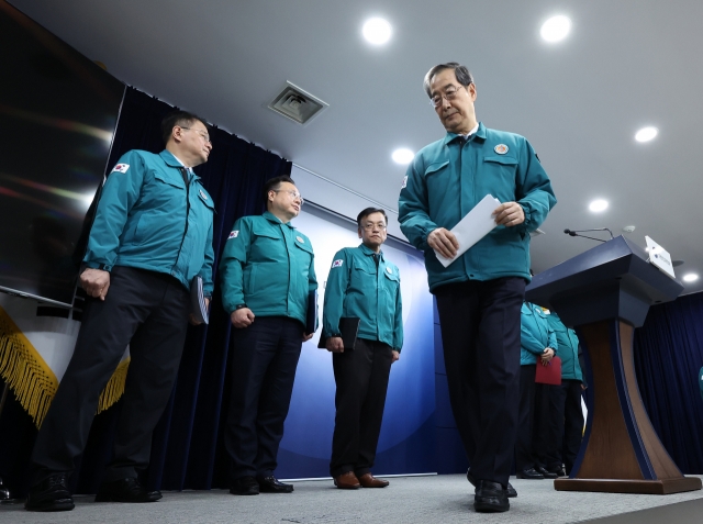 Prime Minister Han Duck-soo, right, leaves after addressing the nation at the Government Complex in Seoul on Wednesday. (Yonhap)