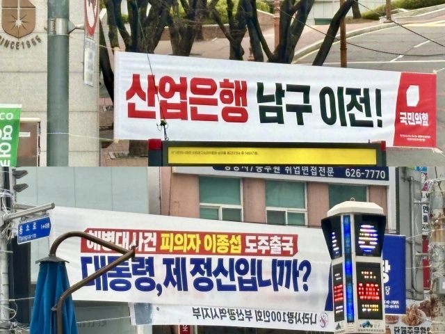 BANNER WARS -- At a busy intersection in Nam-gu, Busan, a banner hung by the People Power Party promotes its pledge to move the Korea Development Bank to Busan. In the image below it, another banner installed by the Democratic Party of Korea nearby reads, “Mr. President, are you out of your mind?” (Kim Arin/The Korea Herald)