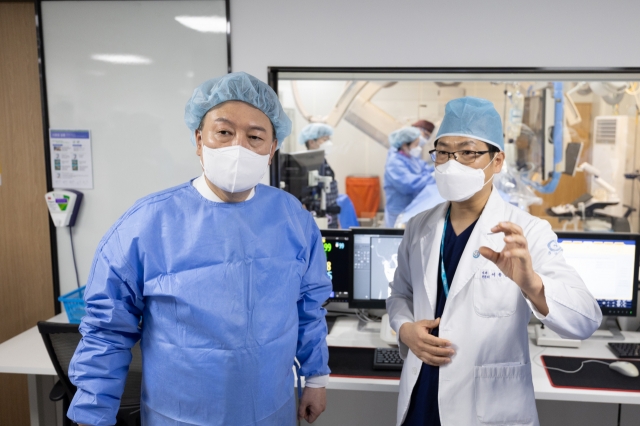 President Yoon Suk Yeol (left) listens to the chief of the cardiovascular center at Hankook General Hospital in Cheongju, 112 kilometers southeast of Seoul, on Tuesday in this photo provided by his office. (Yonhap)