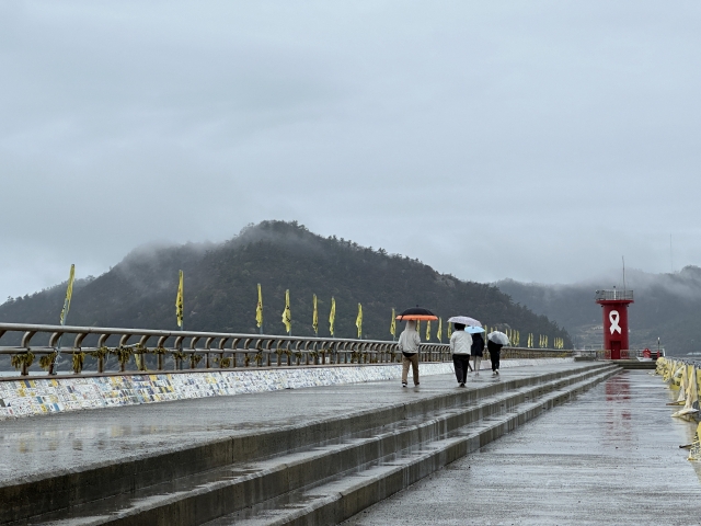 A family walks along the seawall of Jindo Port toward the 