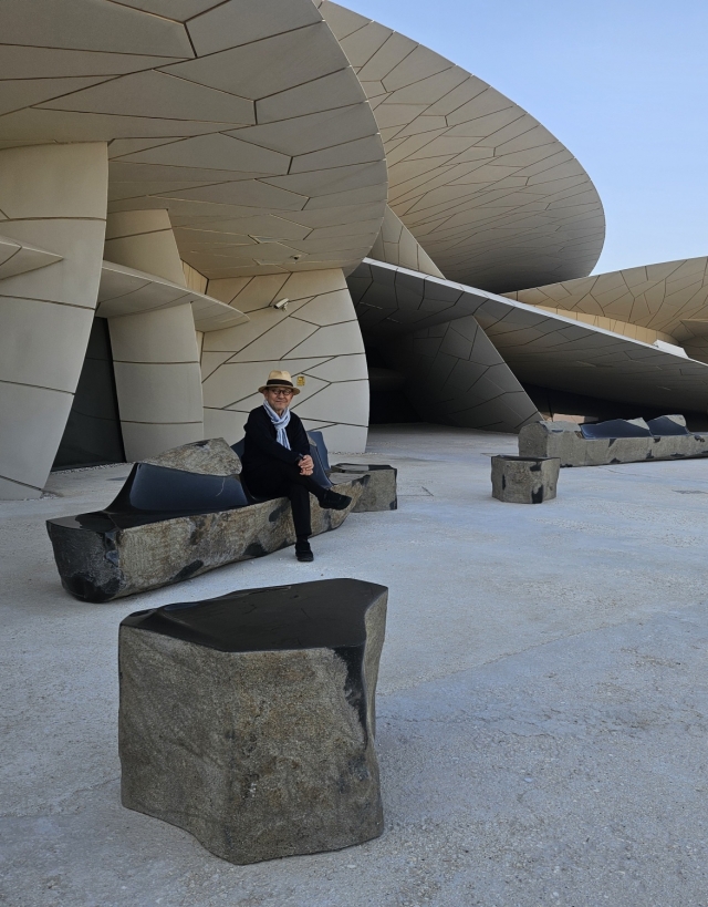 Choi Byung-hoon poses for a photo sitting on his sculpture 