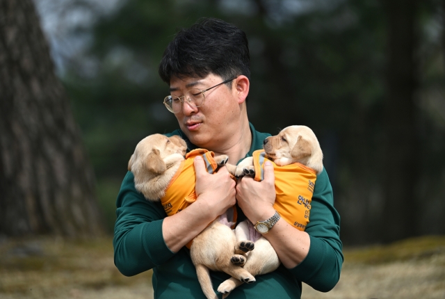 Park Tae-jin holds two puppies at Samsung Guide Dog School in Yongin, Gyeonggi Province, March 27. (Im Se-jun/ The Korea Herald)