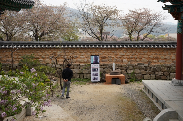 A visitor takes a stroll near a clay fire pit and cast-iron cauldron from 