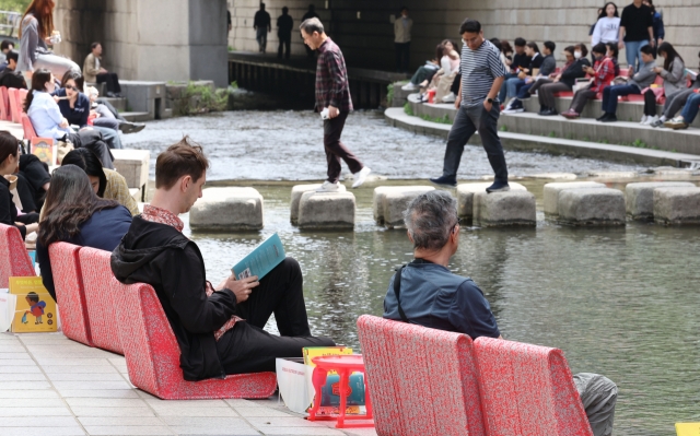 People read books at an outdoor library, which opened along the Cheonggye Stream in central Seoul on Thursday. (Yonhap)