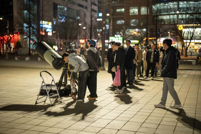 People line up to view the moon through a telescope in a park in Ilsan, northwest of Seoul, in March. (Source: Hong Kee-cheon)