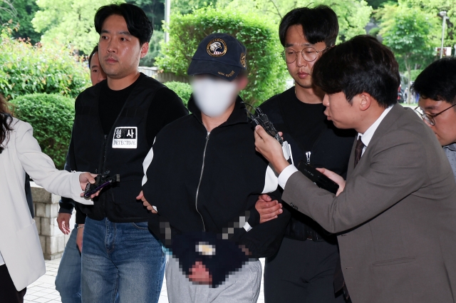 Police officers escort a medical school student accused of murdering his girlfriend for an interrogation at the Seoul Central District Court, Wednesday. (Yonhap)