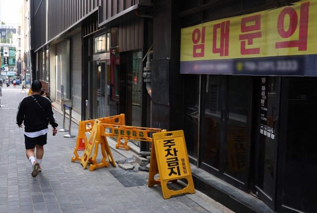 A passerby walks in front of an empty store with a 