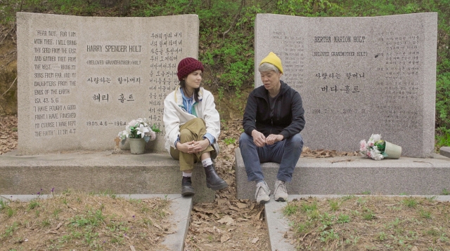 Maite Minh Tam Jeannolin (left) and Korean-born activist kimura byol lemoine sit by the gravestones of Holt Adoption Agency founders Harry and Bertha Holt. (Maite Minh Tam Jeannolin)