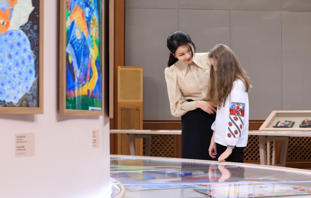 First Lady Kim Keon Hee (left) look around an exhibition by Ukrainian children, Tuesday. (Yonhap)