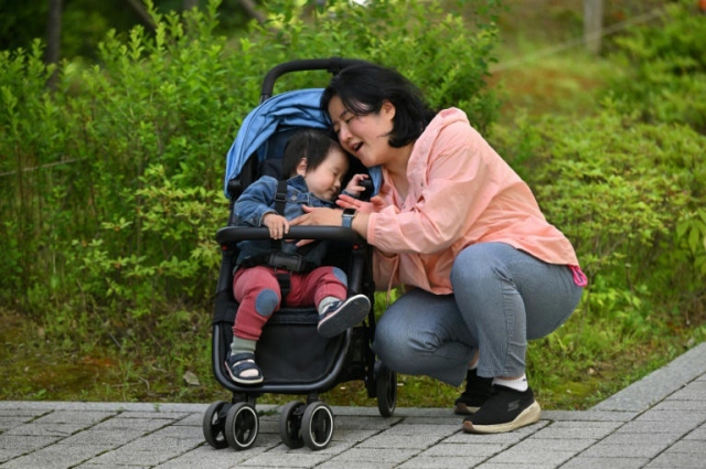 Choi Hee-woo (left) became one the world's youngest plaintiffs when his mother, Lee Dong-hyun, (right) signed him up as the plaintiff in a climate lawsuit while he was still in utero. (AFP)