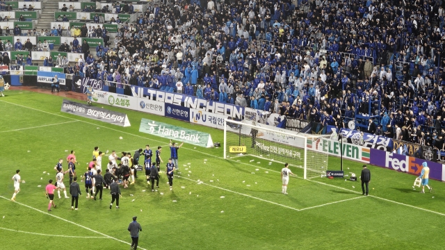 Players from Incheon United and FC Seoul try to stop fans from throwing water bottles onto the field after their K League 1 match at Incheon Football Stadium in Incheon, just west of Seoul, in this file photo taken May 11, 2024. (Yonhap)