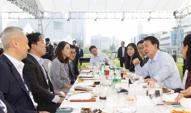 President Yoon Suk Yeol (second from right) speaks with reporters during dinner his office hosted at the presidential office's front lawn on Friday. (Presidential Office)