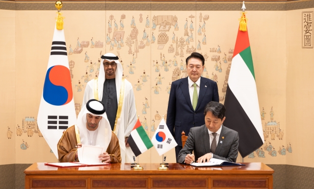 South Korean Industry and Trade Minister Ahn Duk-geun (right, sitting) and his United Arab Emirates (UAE) counterpart, Thani bin Ahmed Al Zeyoudi (left, sitting), sign the Comprehensive Economic Partnership Agreement at the presidential office in Seoul on Wednesday. South Korean President Yoon Suk Yeol (rear, right) and UAE President Mohamed bin Zayed Al Nahyan were in attendance. (Presidential Office)