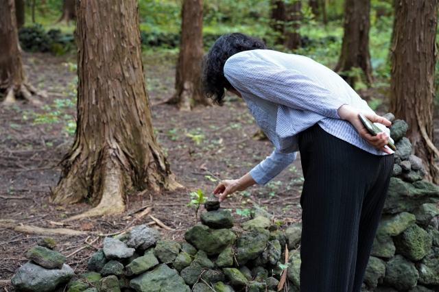 A visitor places a stone on a cairn in the cypress forest surrounding WE Hotel in Seogwipo, southern Jeju Island, May 22. (Lee Si-jin/The Korea Herald)