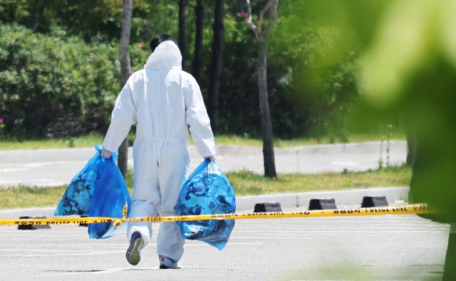 A cleaner takes away bags of trash carried airborne by North Korean balloons in a parking lot outside a shopping mall in Siheung, Gyeonggi Province, on Sunday, (Yonhap)