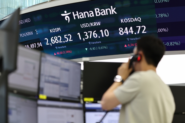 An electronic board showing the Korea Composite Stock Price Index behind a dealer working at a dealing room of the Hana Bank headquarters in Seoul on Monday. (Yonhap)