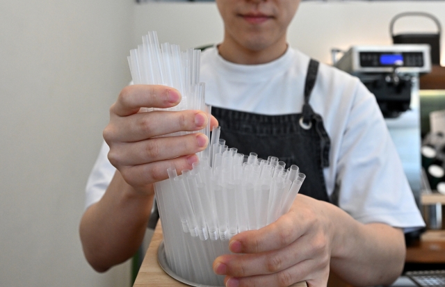 A cafe owner puts plastic straws out for customers following the Ministry of Environment's provisional extension of the grace period to implement its ban on disposable plastics, on November 8, 2023. (Im Se-jun/The Korea Herald)