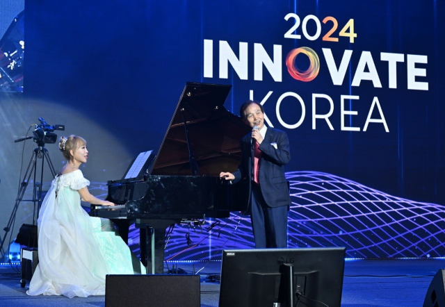 Soprano Sumi Jo (left) and KAIST President Lee Kwang-hyung sing “Yesterday” in an impromptu performance during the Innovate Korea forum held at KAIST Lyu Keun-chul Sports Complex in Daejeon on Wednesday. (Im Se-jun/The Korea Herald)