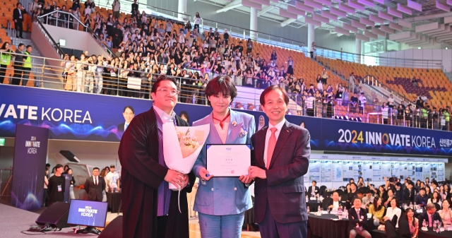 From left: Galaxy Corp. founder and Chief Happiness Officer Choi Yong-ho, G-Dragon and KAIST President Lee Kwang-hyung pose for photos after G-Dragon's appointment as a visiting professor, at the Innovate Korea forum held on the KAIST campus in Daejeon, Wednesday. (Im Se-jun/The Korea Herald)