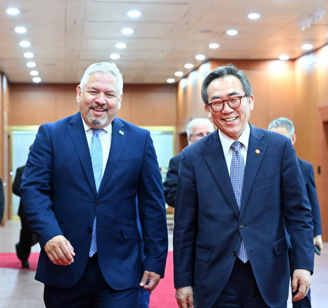 Foreign Minister Cho Tae-yul (right) shares a warm moment with his Honduran counterpart, Enrique Reina, as they stroll through the corridors of Seoul's Foreign Ministry building in Seoul on Sunday. (Ministry of Foreign Affairs)