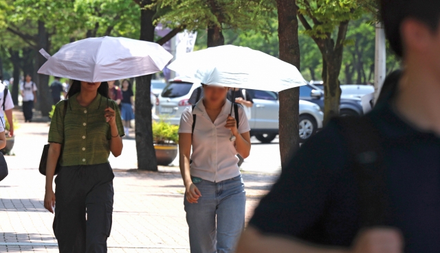 Pedestrians walk with parasols for shade in Gyeongsan, North Gyeongsang Province, Monday. (Yonhap)