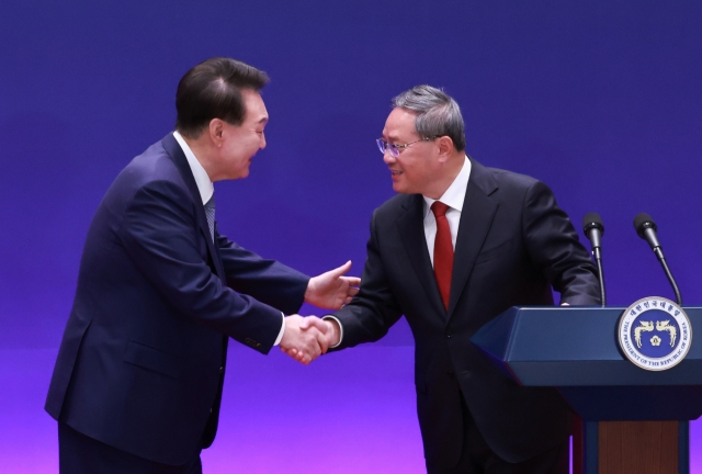 President Yoon Suk Yeol (Left) shakes hands with Chinese Premier Li Qiang after holding a joint press conference with Japanese Prime Minister Fumio Kishida following their trilateral summit in Seoul on May 27. (The presidential office)