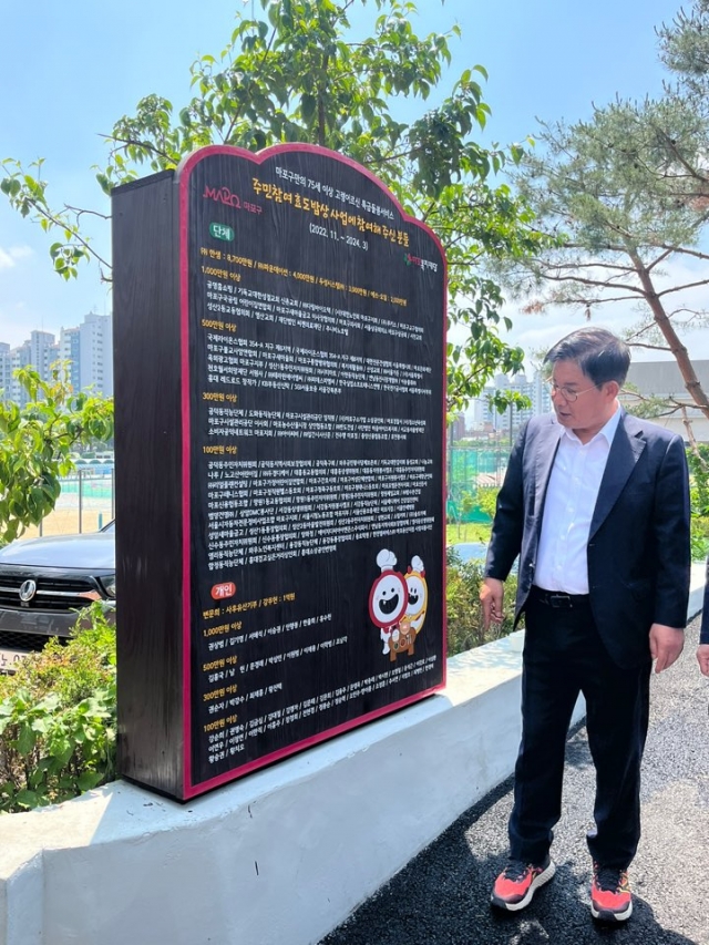 Park Gang-su, the district head of Mapo-gu, introduces the list of donors from local communities for the Hyodo Babsang initiative to reporters in front of a factory producing side dishes for the program in Mapo-gu, Seoul, on May 21. (Lee Jaeeun/The Korea Herald)