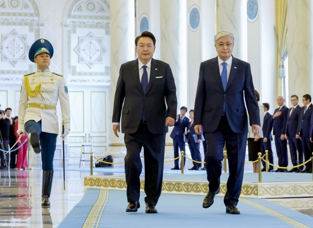 President Yoon Suk Yeol (second from left) and Kazakh President Kassym-Jomart Tokayev (third from left) walk along a carpet as Tokayev received Yoon for a summit held at Akorda Presidential Palace in Astana, the capital city of Kazakhstan, on Wednesday. (Yonhap)