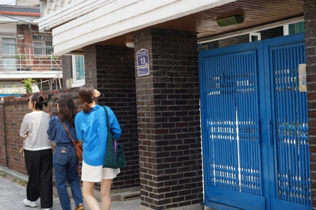 Visitors pass by the iconic blue gate of Seon-jae's house from 