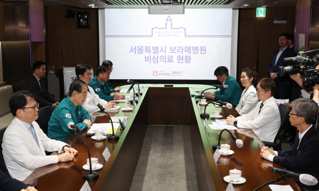 Prime Minister Han Duck-soo (left) speaks with doctors at SNU Boramae Medical Center in southern Seoul on Friday. (Yonhap)