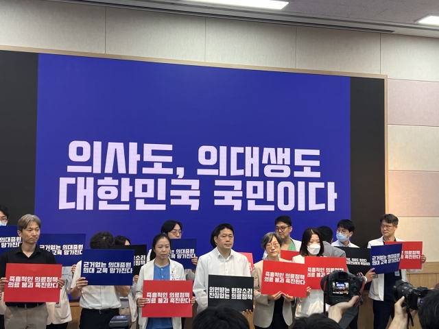 Medical professors at Seoul National University hold up picket signs urging the government to suspend medical reform at the school's campus in central Seoul on Monday. (Park Jun-hee/The Korea Herald)