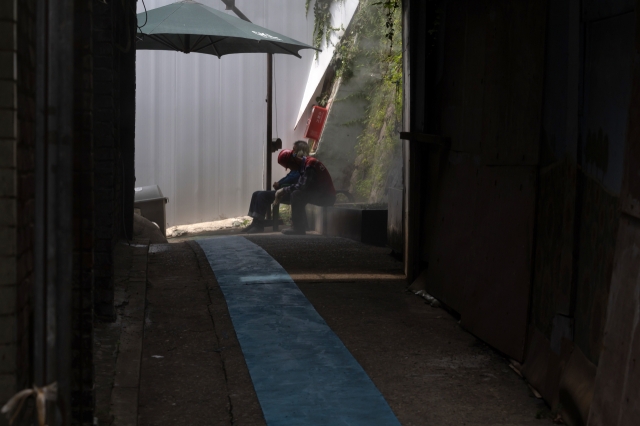 A construction worker rests in the shade in cooling mist near Seoul Station on June 21, as the daytime high reached 33 degrees C. (Yonhap)