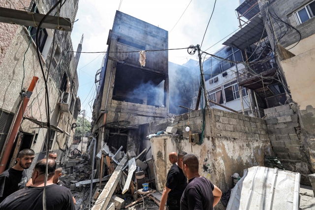 People inspect a building that was heavily damaged during an Israeli army raid on the Nur Shams camp for Palestinian refugees, east of Tulkarm in the occupied West Bank, on Monday. (AFP-Yonhap)