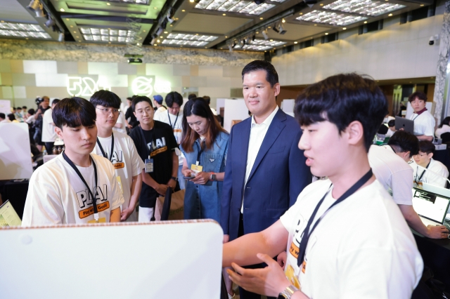 GS E&C CEO Huh Yoon-hong (second from right) listens to participants explaining their projects during the GS Group 2024 Hackathon held at a Seoul hotel on Wednesday. (GS Group)