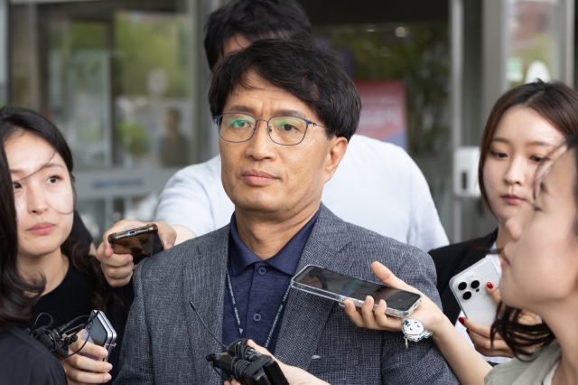 A police officer is surrounded by reporters after stepping out from an interrogation session at a Seoul hospital on Thursday, to question the driver involved in a deadly car crash that killed nine pedestrians in central Seoul earlier in the week. (Yonhap)