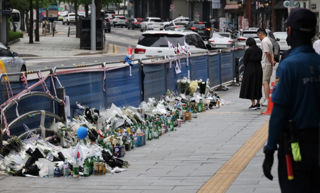 Bouquets of white chrysanthemums, drinks and commemorative messages are laid near Exit No. 7 of City Hall Station, Sunday, six days after a deadly car crash that resulted in nine casualties. (Yonhap)