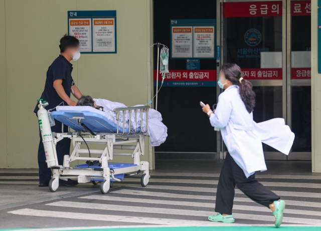 A medical staff at the emergency room of Asan Medical Center in Seoul is moving a patient on a gurney on July 3. (Yonhap)