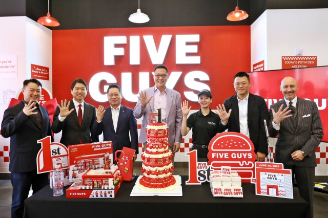 Hanwha Galleria Strategy Division Head Kim Dong-sun (center), participates in a cake cutting ceremony with officials at the Five Guys’ first branch in Gangnam, celebrating the branch's first anniversary, on June 26 (FG Korea).